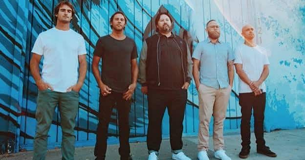Members of the reggae band Iration posing in front of a blue wall