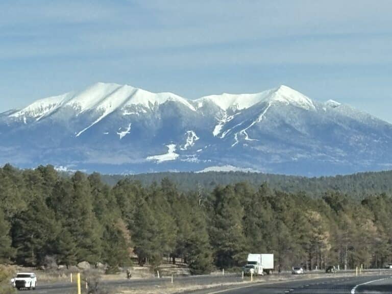 Snow-capped San Francisco Peaks rising above a pine forest west of Flagstaff, Arizona