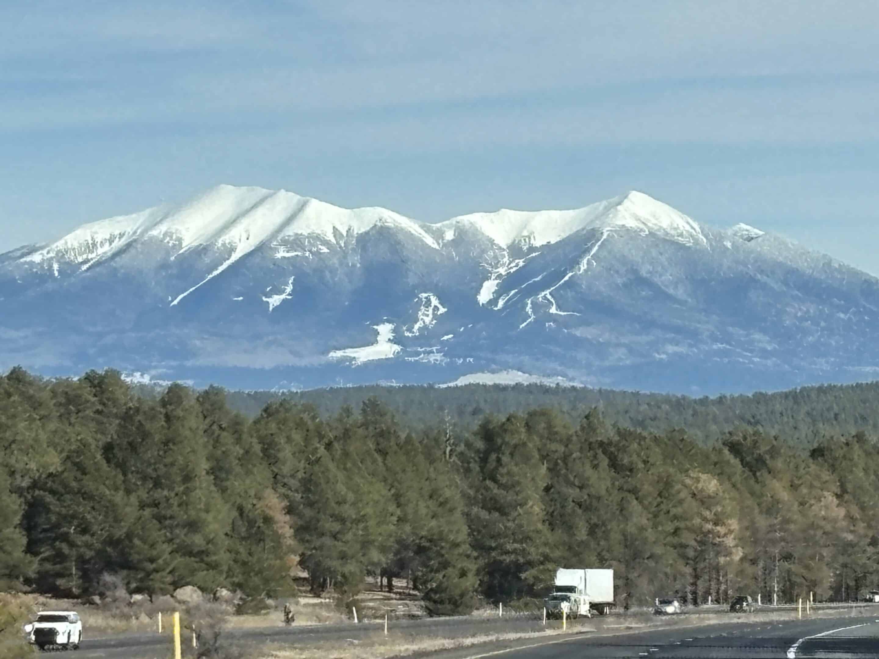 Snow-capped San Francisco Peaks rising above a pine forest west of Flagstaff, Arizona