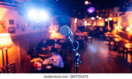 Dimly lit bar with stage lights and a microphone set up for karaoke night